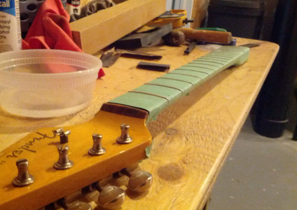 Frets masked off with tape to protect the fingerboard.